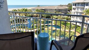 A balcony with a view of a resort area, including a pool and a building with multiple balconies. - Spacious 5th Floor 2 BR Villa w/ Amenities (Hilton Head Island)