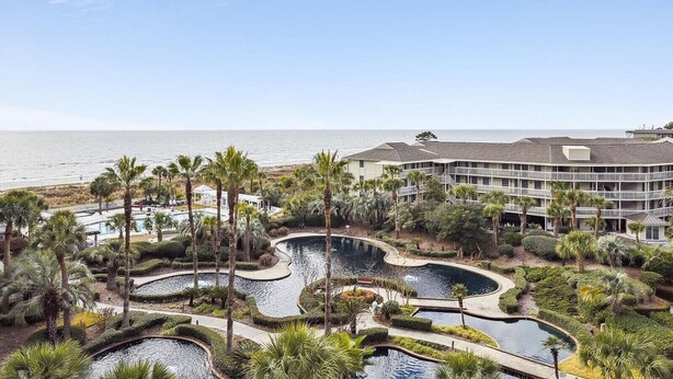 A resort with multiple swimming pools, palm trees, and a view of the ocean. - Enjoy 5th Floor Views of the Ocean & Amenities (Hilton Head Island)
