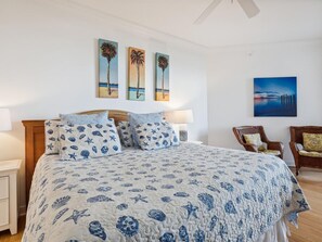 Ein Schlafzimmer mit einem großen Bett, zwei an der Wand befestigten Bildern und einem Sessel.