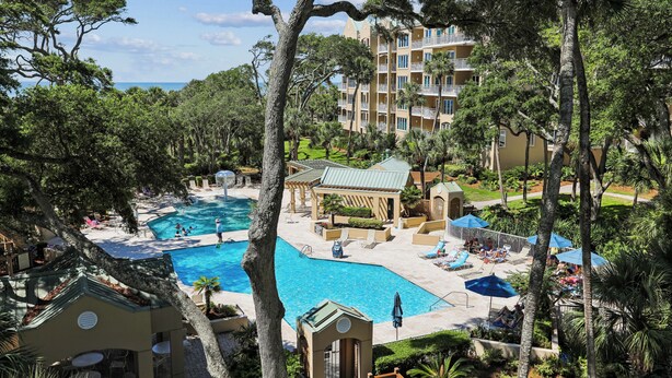 Un resort con piscina, lettini e un edificio con balconi.
