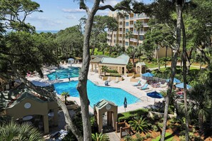 A resort with a swimming pool, lounge chairs, and a building with balconies. - Ocean Front 4Br Villa w/ Large Balcony! (Hilton Head Island)