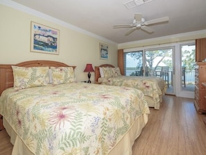 A bedroom with two beds, a ceiling fan, and a balcony with a view. - 1898 Beachside Tennis ~ 4th Floor Villa with Fantastic Water Views & Free Tennis (Hilton Head Island)