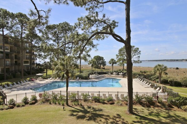 Relax by the resort pool surrounded by lush views of the surrounding landscape and a distant shoreline.