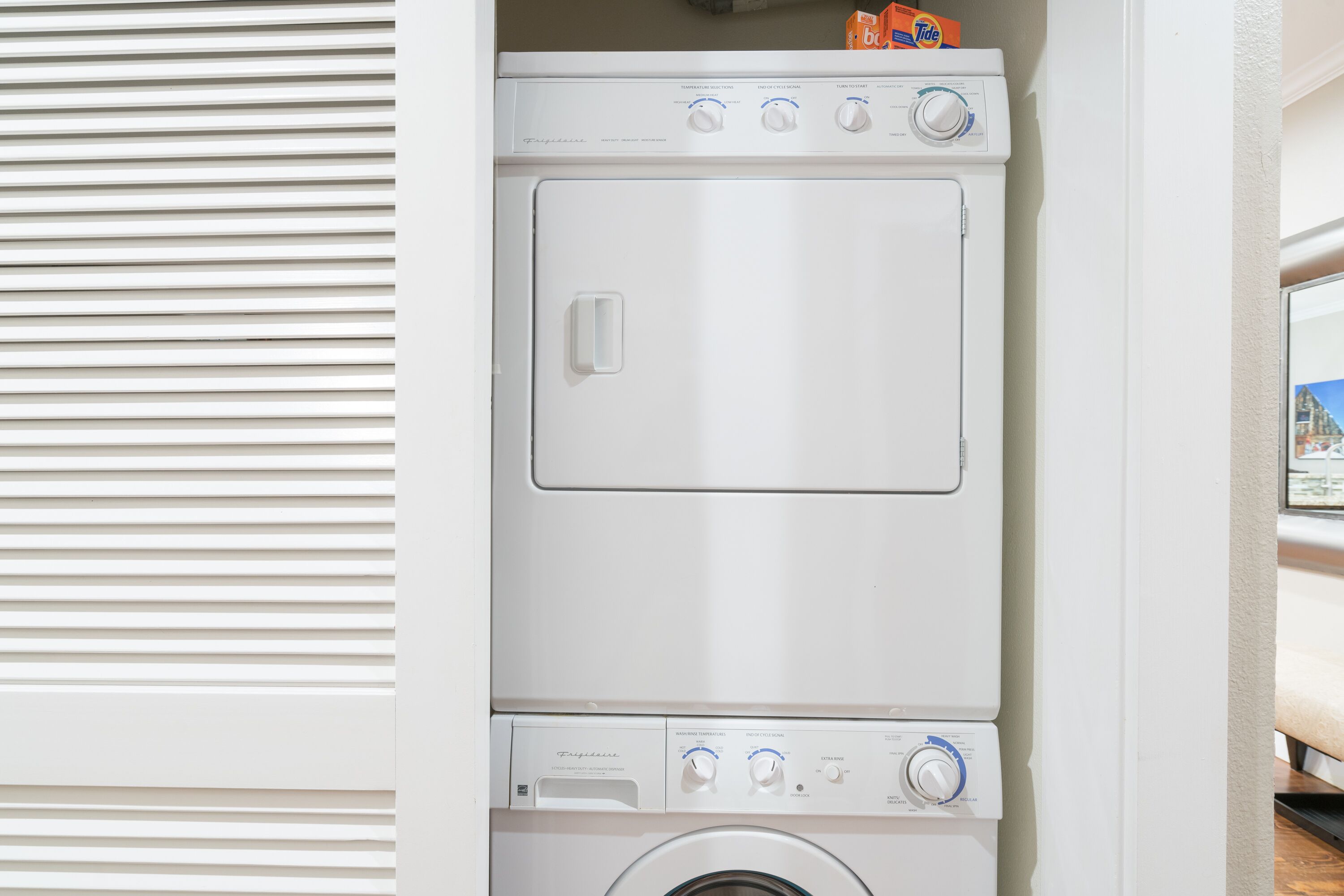 A white stacked washer and dryer unit with control knobs and a door handle.