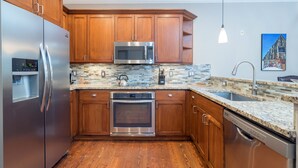 Una cucina moderna con mobili in legno, elettrodomestici in acciaio inossidabile e rivestimento a mosaico.