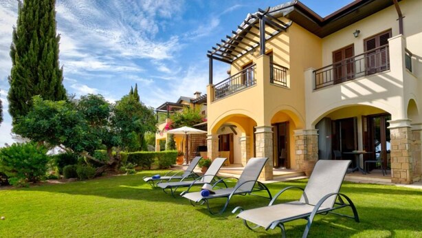 A hotel with a patio area featuring lounge chairs and a well-maintained garden. - Apartment A02 - Roudias (Kouklia)