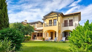 A two-story house with a balcony, a well-maintained lawn, and a clear sky. - Apartment A02 - Roudias (Kouklia)