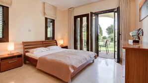 A bedroom with a bed, bedside tables, a desk, and a view of the outdoors. - Apartment A02 - Roudias (Kouklia)