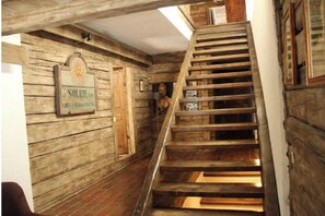Step into the charming Au Soleil, where a rustic staircase and wooden accents create a warm atmosphere.