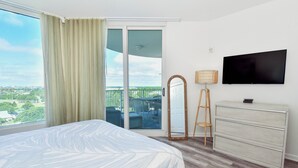 A hotel room with a bed, a television, a dresser, and a balcony with a view of the city. - Beautiful Views from the 10th Floor of The Palms of Destin! (Destin)