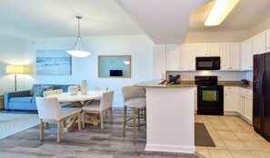 A modern kitchen with white cabinets, a black refrigerator, and a microwave.