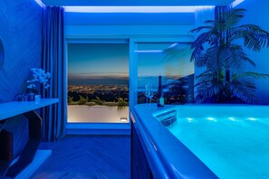 A modern bathroom with a large bathtub, a view of a cityscape, and a potted palm tree. - Luxury Villa Seventh Heaven with heated pool, hot tub, gym, panoramic views (Klis)