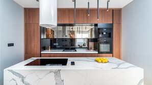 A modern kitchen with a marble island, built-in appliances, and pendant lighting. - Luxury Villa Seventh Heaven with heated pool, hot tub, gym, panoramic views (Klis)