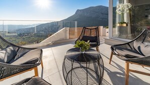 A balcony with wicker chairs and a small round table, overlooking a cityscape and mountains. - Luxury Villa Seventh Heaven with heated pool, hot tub, gym, panoramic views (Klis)