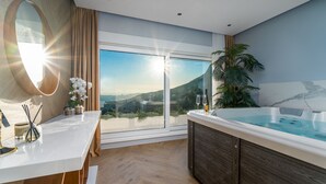A modern bathroom with a large window, a hot tub, and a wooden vanity. - Luxury Villa Seventh Heaven with heated pool, hot tub, gym, panoramic views (Klis)