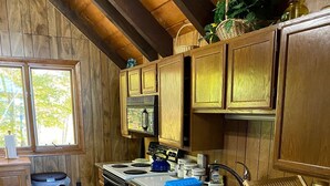 A kitchen with wooden cabinets, a stove, a microwave, and a sink. - 6 bedroom waterfront cabin -enjoy beautiful sunsets! (Frye Island)