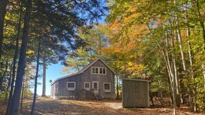 A rustic wooden house surrounded by trees with autumn leaves. - 6 bedroom waterfront cabin -enjoy beautiful sunsets! (Frye Island)