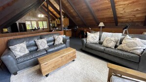 A spacious loft with two leather sofas, a wooden coffee table, and a patterned rug. - 6 bedroom waterfront cabin -enjoy beautiful sunsets! (Frye Island)