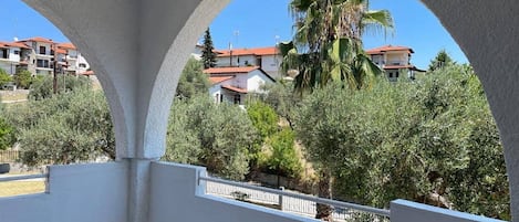 A balcony with a view of a residential area, including houses and a palm tree.