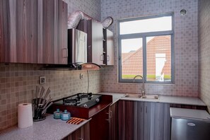 Een koelkast, een broodrooster, kookgerei, borden en bestek, kruiden