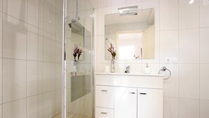 A modern bathroom with a glass shower enclosure, a white vanity with a mirror, and a vase with flowers. - MARCOS. Beautiful apartment in Puerto Pollensa (Puerto Pollensa)