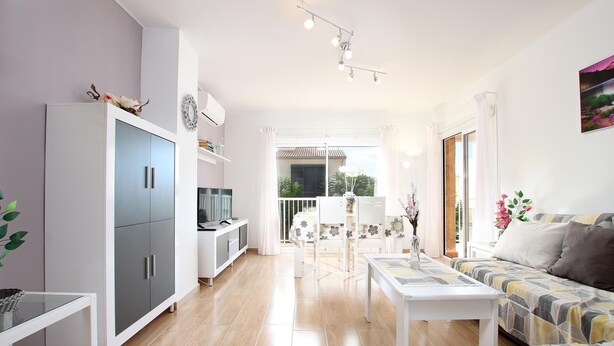 A modern living room with a sofa, a dining table, and a kitchen area with cabinets and a TV. - MARCOS. Beautiful apartment in Puerto Pollensa (Puerto Pollensa)