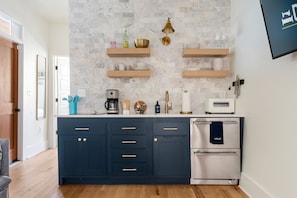 A modern kitchen with dark blue cabinets, a built-in oven, and a marble backsplash.