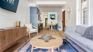 A modern living room with a sofa, a round wooden coffee table, and a TV mounted on the wall. - Only 2 Blocks to King! | The Murray (Charleston)