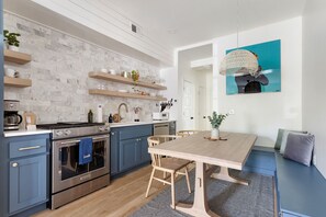 Une cuisine moderne avec des meubles bleus, une table à manger en bois et un luminaire suspendu.