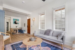 Un salon avec un canapé gris, une table basse ronde en bois et un tapis bleu à motifs.