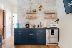 A modern kitchen with dark blue cabinets, a white oven, and a marble backsplash.