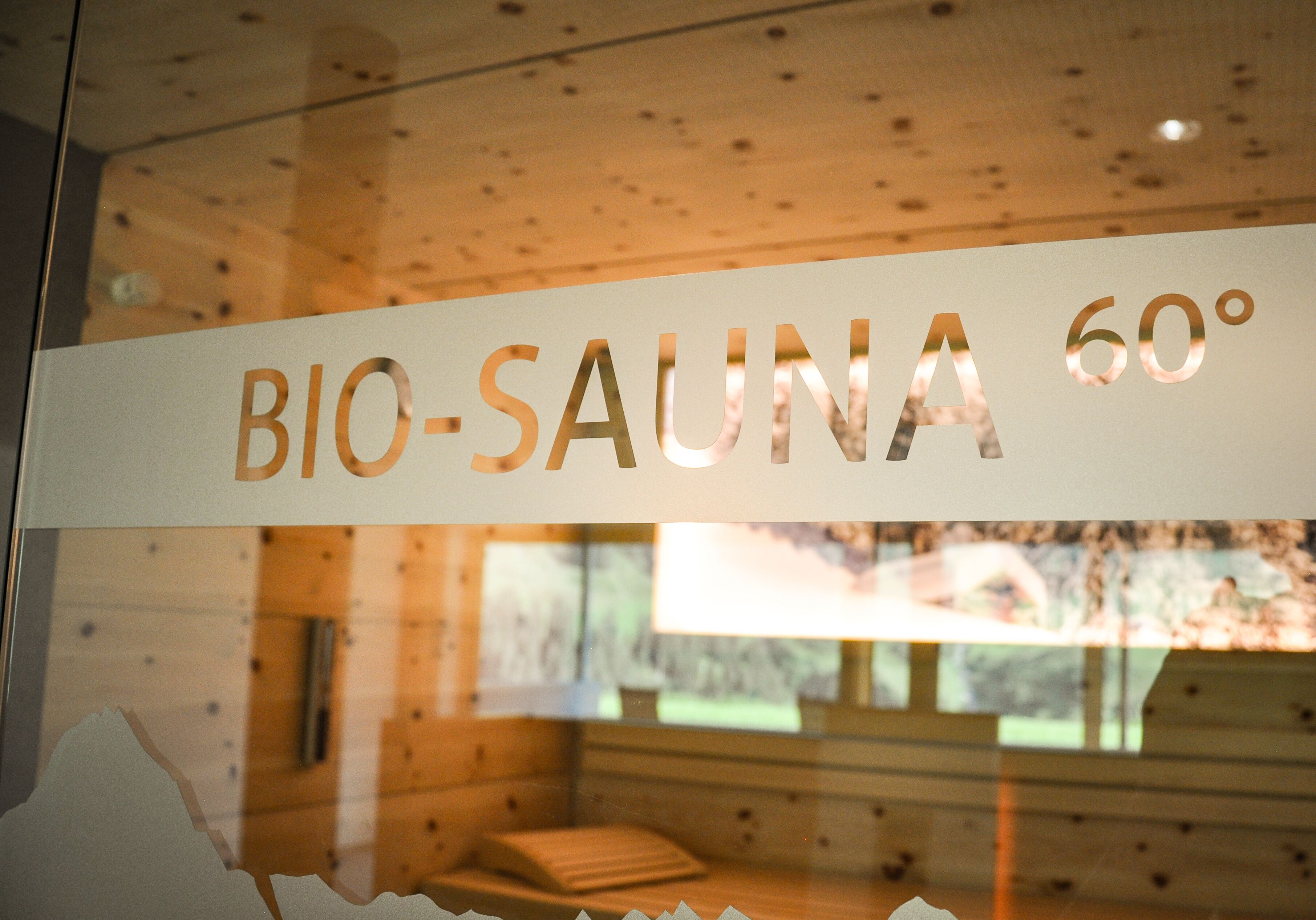 A sign reading "BIO-SAUNA 60°" in a wooden cabin interior.