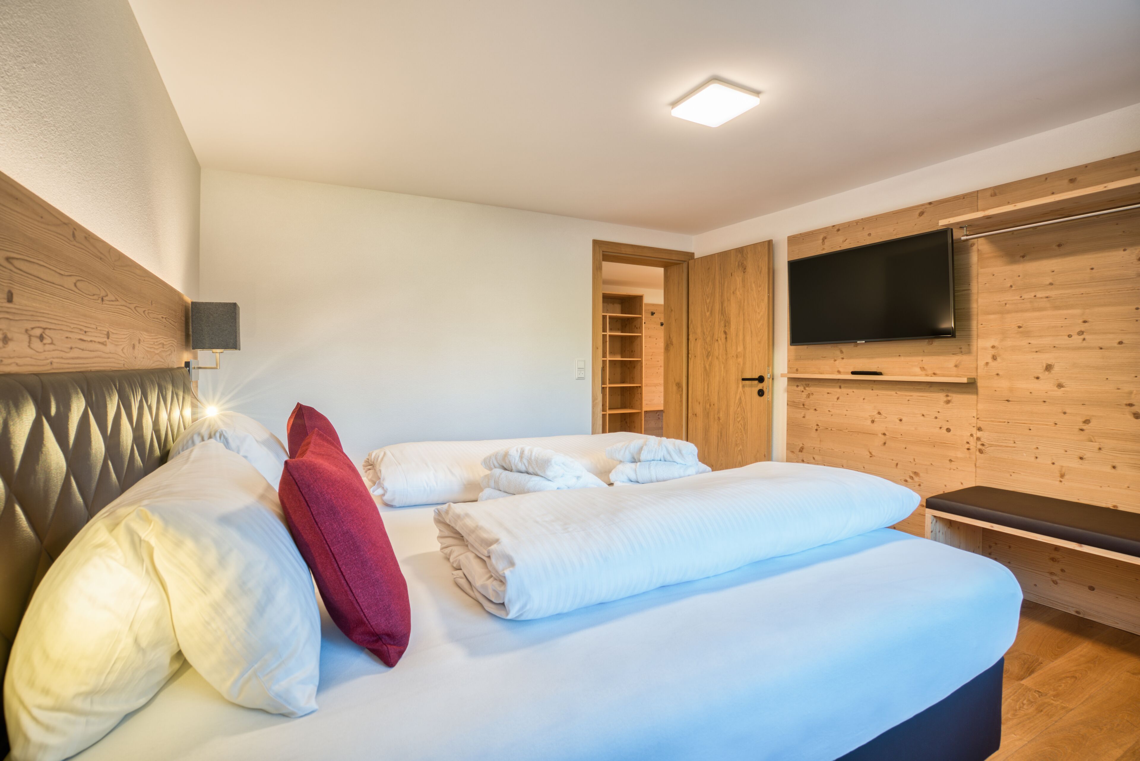 A bedroom with a bed, pillows, a TV, and wooden paneling.