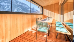 A modern interior with a wooden floor, a large table with chairs, and a view of snow-capped mountains through a large window. - HUS 23 (Schroecken)