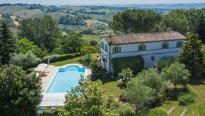Une villa avec piscine, entourée d’une végétation luxuriante et avec des collines en arrière-plan.
