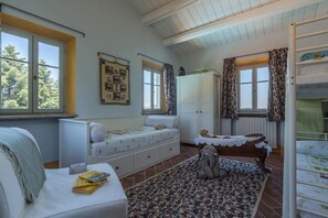 Cozy retreat with a high ceiling, featuring a plush bed, sofa, and reading nook.