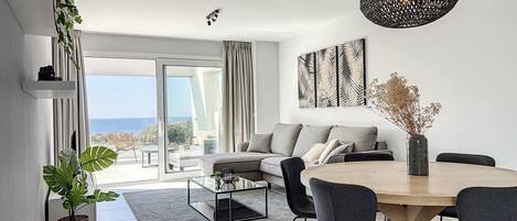 Uma sala de estar moderna com sofá, mesa de centro e área de jantar.