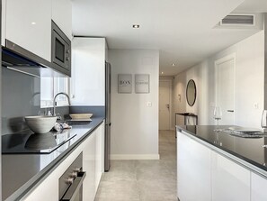 A modern kitchen with a large island, built-in appliances, and a minimalist design.