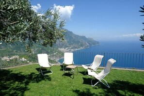A terrace with white chairs and a view of the sea.