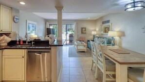 A modern kitchen with a dishwasher, a dining area with a table and chairs, and a living room with a sofa and a TV. - Walk to Beach!  Comfortable Chic Hilton Head Villa (Hilton Head Island)