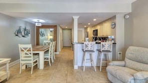 A modern kitchen with white cabinets, a central island, and bar stools.