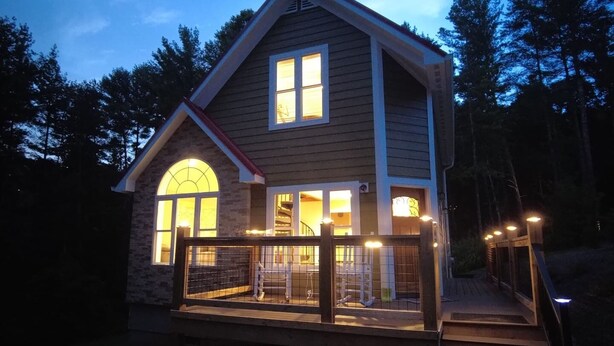 A two-story house with a wooden deck and a staircase leading to the entrance. - Dogwood Cottage (Weaverville)