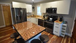 A modern kitchen with granite countertops, stainless steel appliances, and white cabinetry. - Dogwood Cottage (Weaverville)