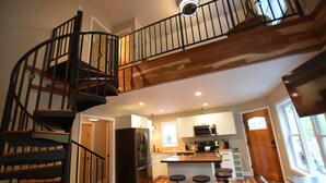 A kitchen with a central island, wooden flooring, and a spiral staircase. - Dogwood Cottage (Weaverville)