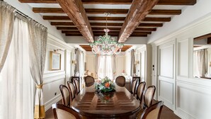 Comedor con techo de madera, una araña y una mesa redonda con sillas.