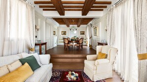 Amplia sala de estar con techo de madera, comedor y sofá con cojines estampados.