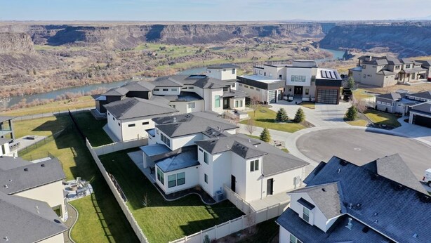 Un quartier résidentiel avec des maisons modernes, une allée centrale et une rivière en arrière-plan.