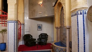 Una habitación con alfombra roja, dos sillones de cuero negro, una mesita y un cuenco decorativo grande.