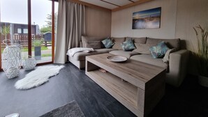 A modern living room with a sofa, a coffee table, and a large window with curtains. - RBR 181 - Beach Resort Kamperland (Kamperland)