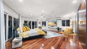 A modern bedroom with a large bed, a sofa, and a TV. - Bayfront Villa Heated Pool Amazing Views and Beach Access (North Bay Village)